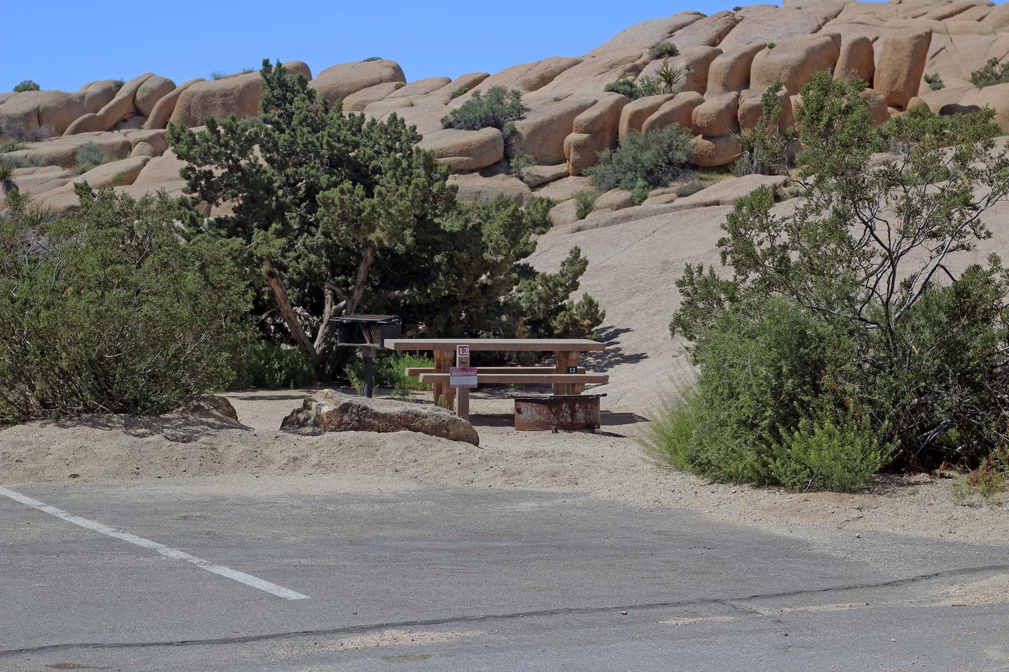  Shared parking for campsite. Picnic table surrounded by boulders and green plants.Shared parking for campsite.
