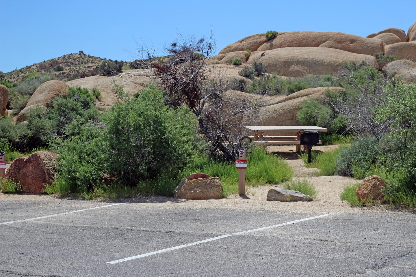 Shared parking for campsite. Picnic table surrounded by boulders and green plants.
Shared parking for campsite.
