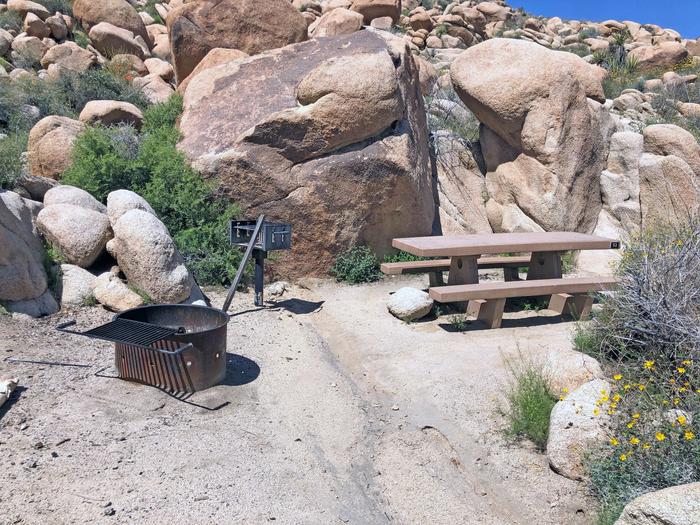 Campsite  with picnic table surrounded by boulders and green plants.Campsite.