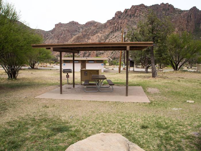Chisos Basin Campsite #24 overviewView showing shade ramada with grill, bear box, and picnic table inside. Note restroom in background.