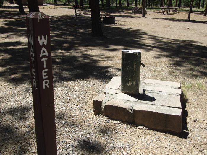 Brown sign with "WATER" engraved on it in front of a water pumpWater is available when freezing temperatures are not present (typically mid-April to mid-October).