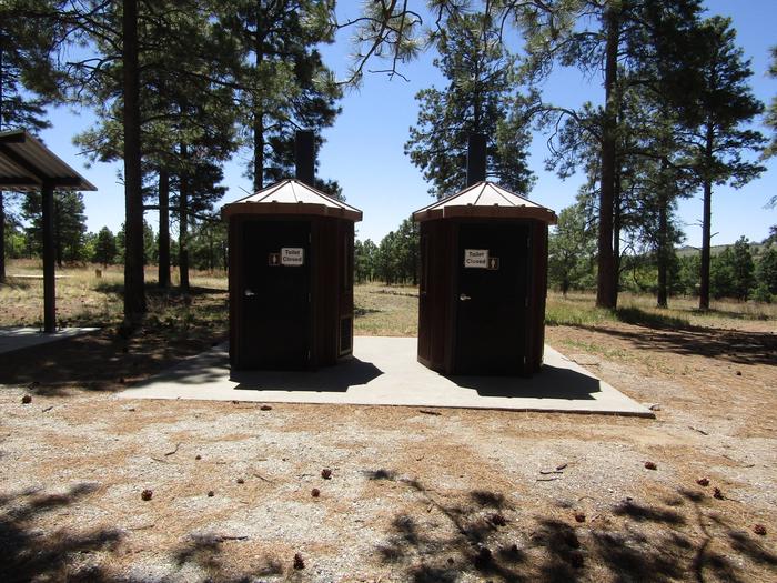 Vault toilets in front of tall pinesVault toilets are available to campers at Ponderosa Group Campground. No running water in restrooms or shower facilities are available. 