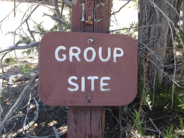 Brown wooden sign with "Group Site" engraved on it.Juniper Family Campground is home to two (2) group campsites that accommodate 10-20 campers each.