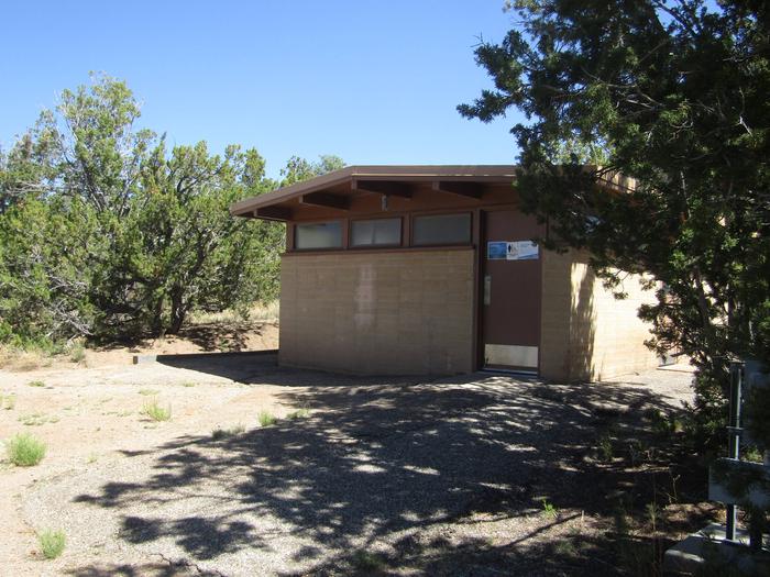 A tan brick building surrounded by juniper.Restrooms with running water (no shower or laundry facilities in the park) are centrally located in all loops of Juniper Family Campground.