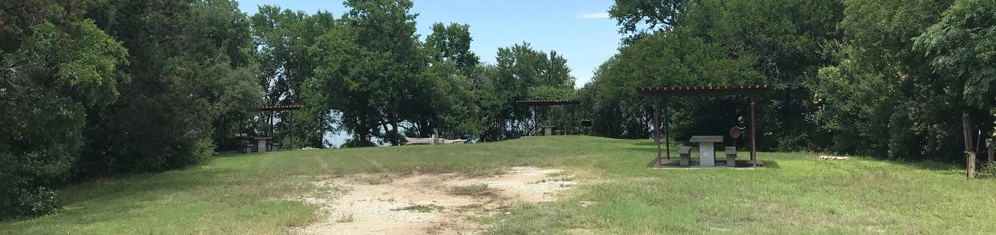RV site with covered picnic table, grill, and Waco Lake in the backgroundGroup site