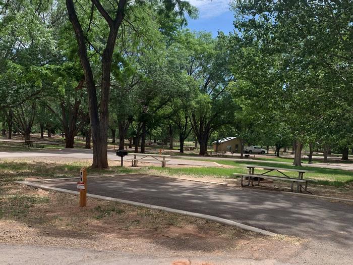 A paved driveway. Facing the end of the driveway, a picnic table is off to the right side and a fire pit is directly behind it. A tree is directly behind the end of the driveway. Site 3, Loop A in summer. Admin Site.
Paved Dimensions: 14' x 39'