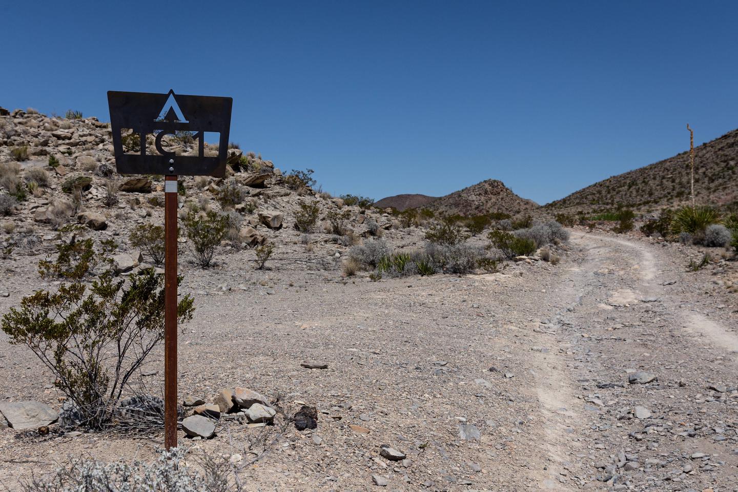 Camping area with desert mountain backgroundCampsite marker and access road to campsite
