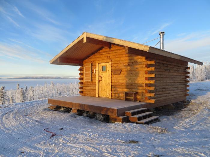 A log cabin on a snowy ridge under clear skiesMoose Creek Cabin in winter