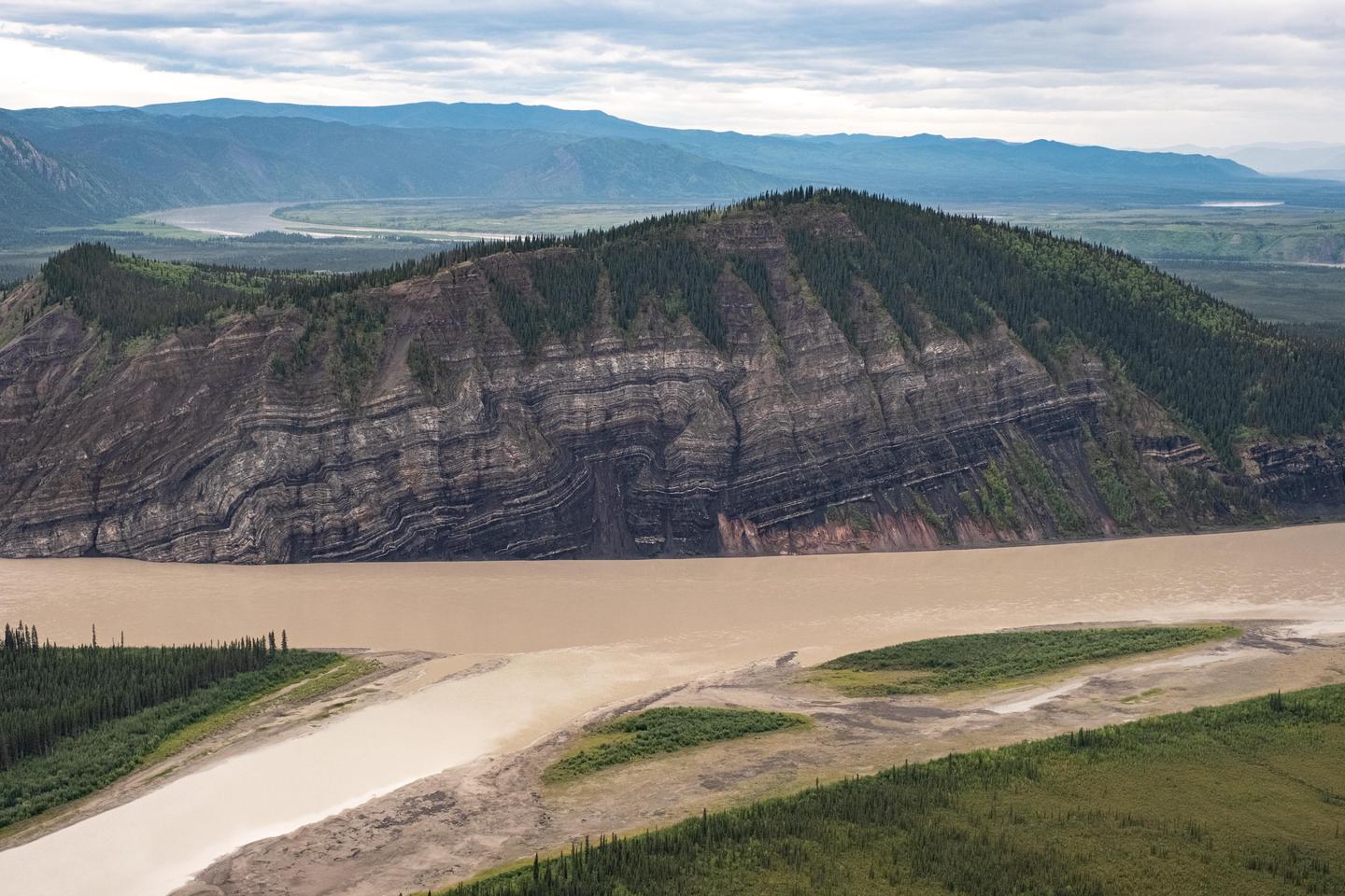 Calico Bluff and the Yukon RiverCalico Bluff, showing 4 million years of rock layers, rises above the Yukon River and is one of many bluffs along the 130 miles of river in the preserve