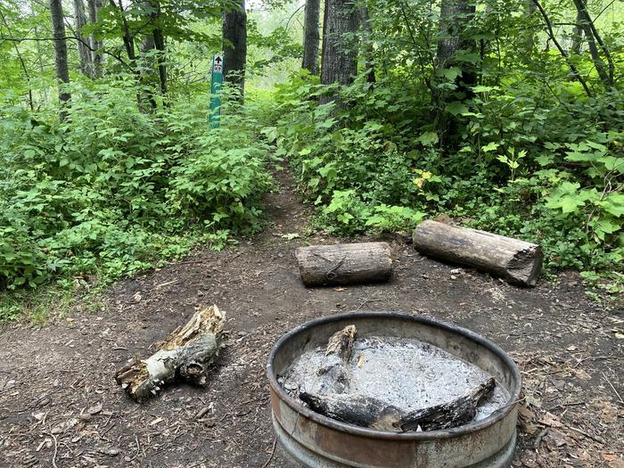 Shared campfire ring and sign to the pit toilet.