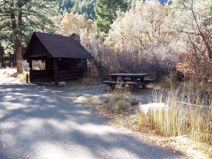 Site 15 with a shelter unit, picnic table, fire ring, and parking.