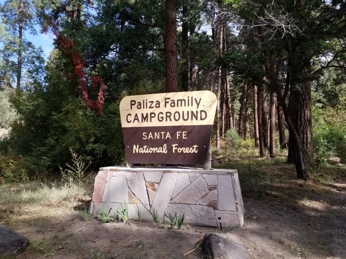 The entrance sign of Paliza Family campground surrounded by pines in the background.Paliza Family Campground entrance sign.
