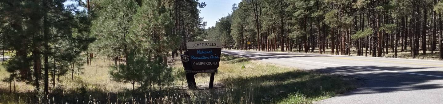 The entrance to Jemez Falls sign with pine forests in the background.Jemez Falls campground entrance.