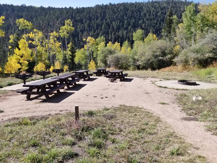 A campground with picnic tables, fire ring and golden aspen in the background.Jack's Creek Group Area Site A