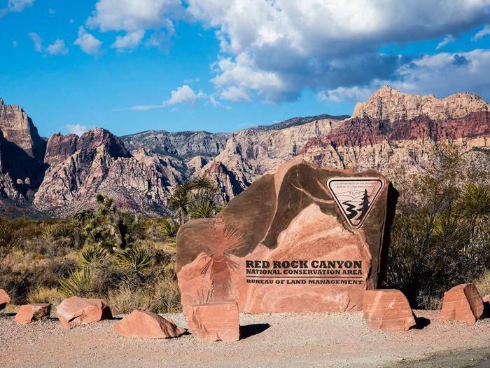 Red Rock Canyon entrance sign with mountains in the background. Red Rock Canyon welcomes visitors.