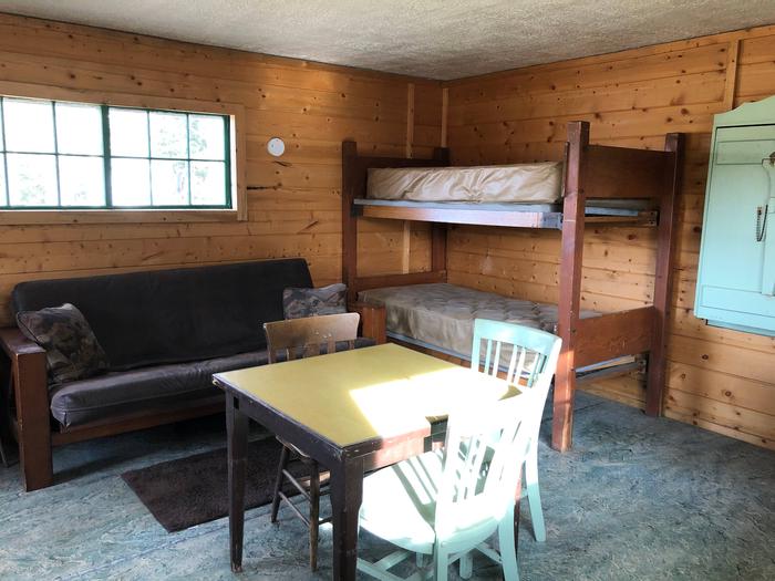 Cabin interior showing futon couch, bunkbeds and kitchen tableCabin Interior