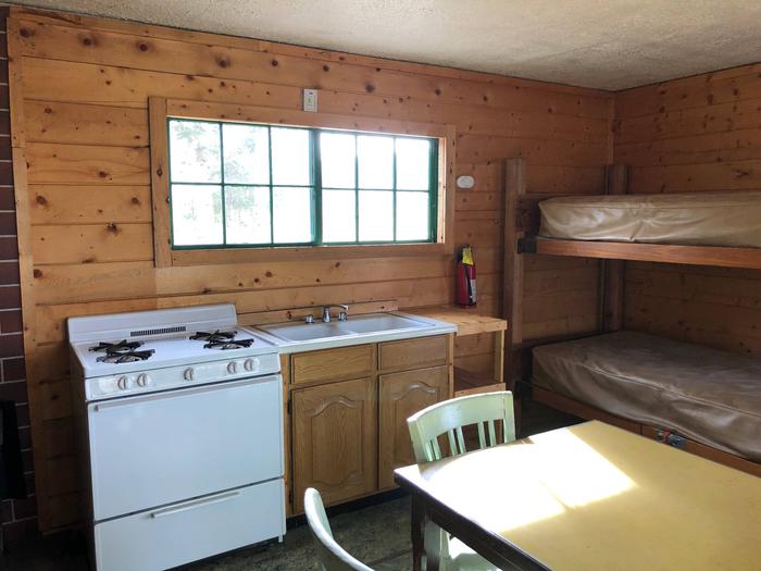 Cabin interior showing gas range, bunkbeds, table and dry sink Cabin Interior