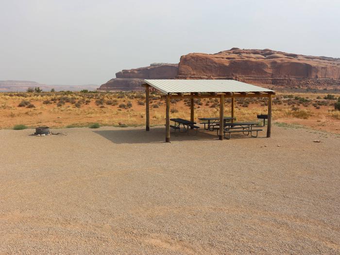 Lone Mesa Group Site B shade shelter and picnic tables. Red rock cliffs in the distance.