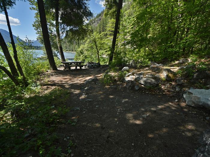 A wooded campsite with picnic table and views of a lake and hillsPurple Point Site 3