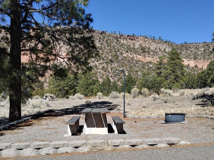 A picnic site with juniper, pines, and a mesa in the background.