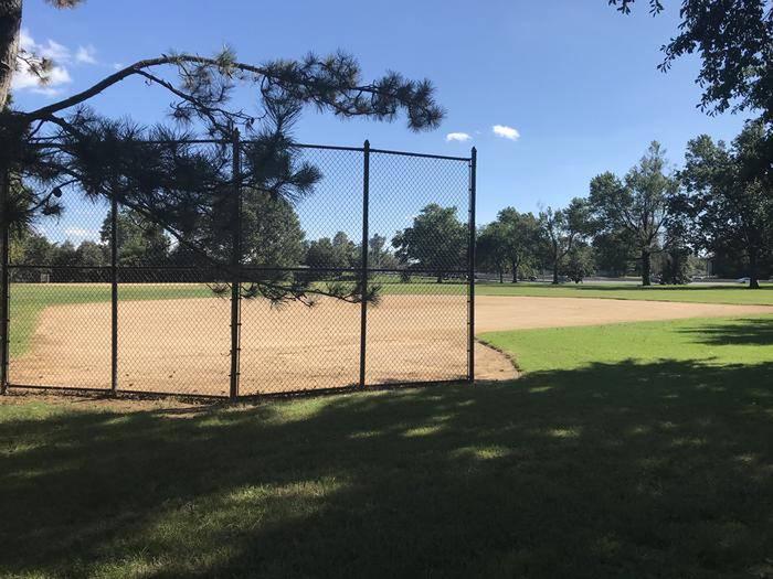 The photo shows field S9 with a backstop, infield, and grassy outfield. There are scattered trees in the background.Field S9