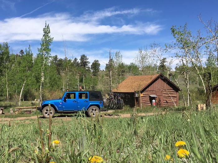 Bassam Guard Station exterior with vehicle parked outsideCabin surrounded by Aspen grove