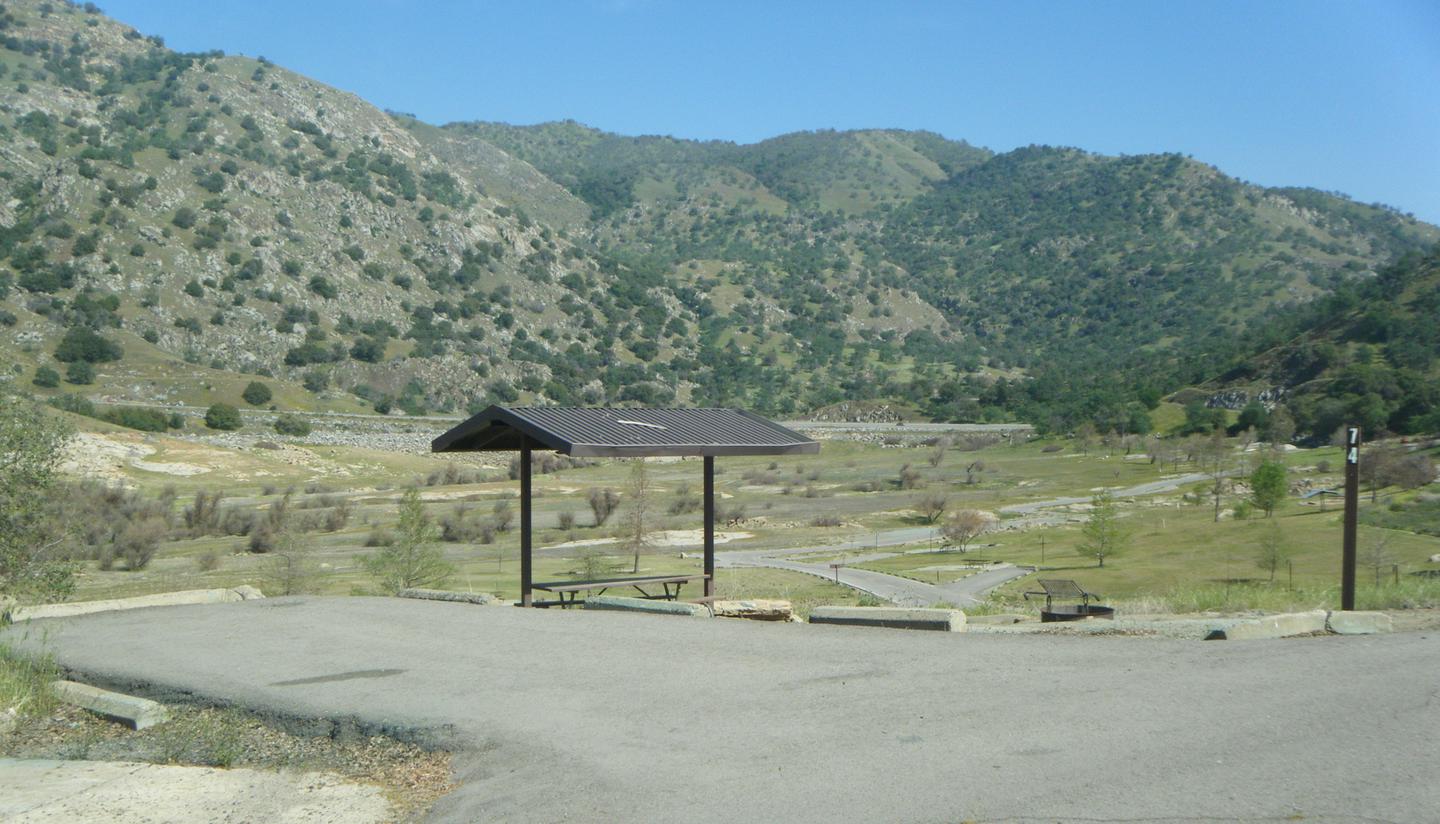 Campsite with a parking pad for one vehicle. This site has a shade cover over the table and a campfire ring. It is on a hill so the road is one way. The parking pad is short and parking is very limited. 
