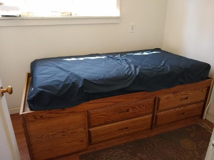 A twin sized mattress with storage underneath.One of two bedrooms, each with a twin-sized bed.