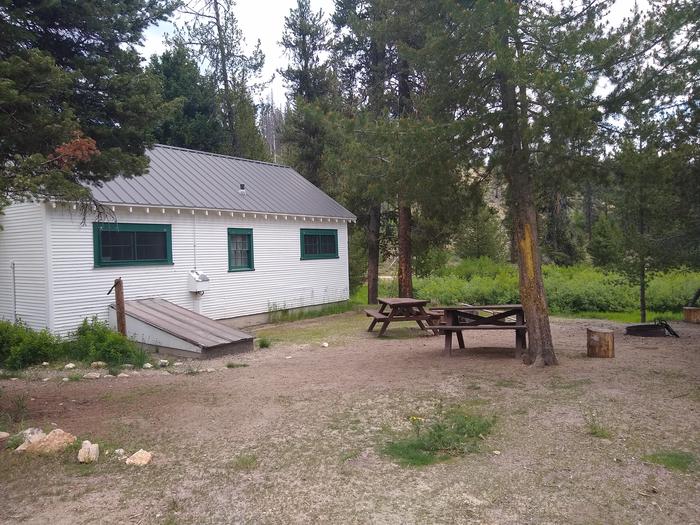 A cabin next to picnic tables and a fire ring.Beaver Creek cabin features a spacious yard with picnic tables and a fire ring.