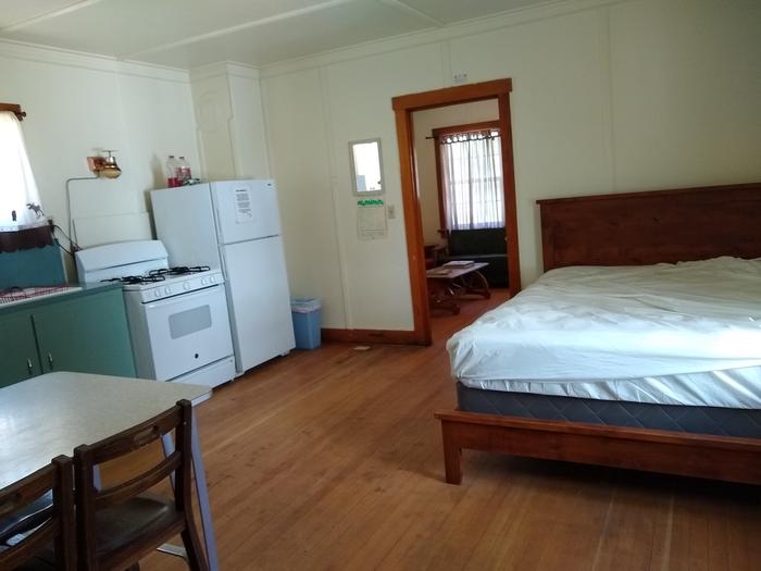 A room with a big bed, stove, sink, refrigerator, and table.Atlanta Cabin's combination kitchen/bedroom/dining room.