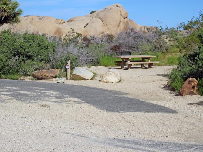 Parking for campsite. Picnic table surrounded by boulders and green plants.Parking Site 94