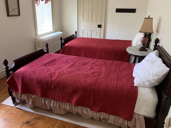 Room with two twin beds with red bedspreadsUpstairs Bedroom 1