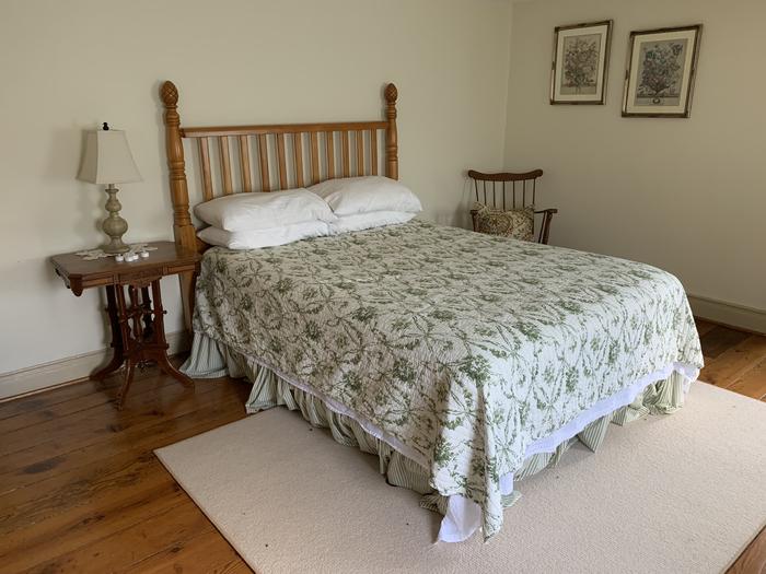 Room with wooden bed  with flowered bedspread, side table and lampUpstairs Bedroom 2