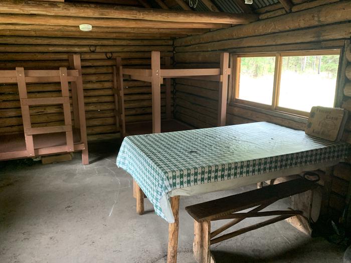 Inside Twogood Cabin dinning / sleeping areaInside a rusting cabin is two bunkbeds and a dinning table and chairs