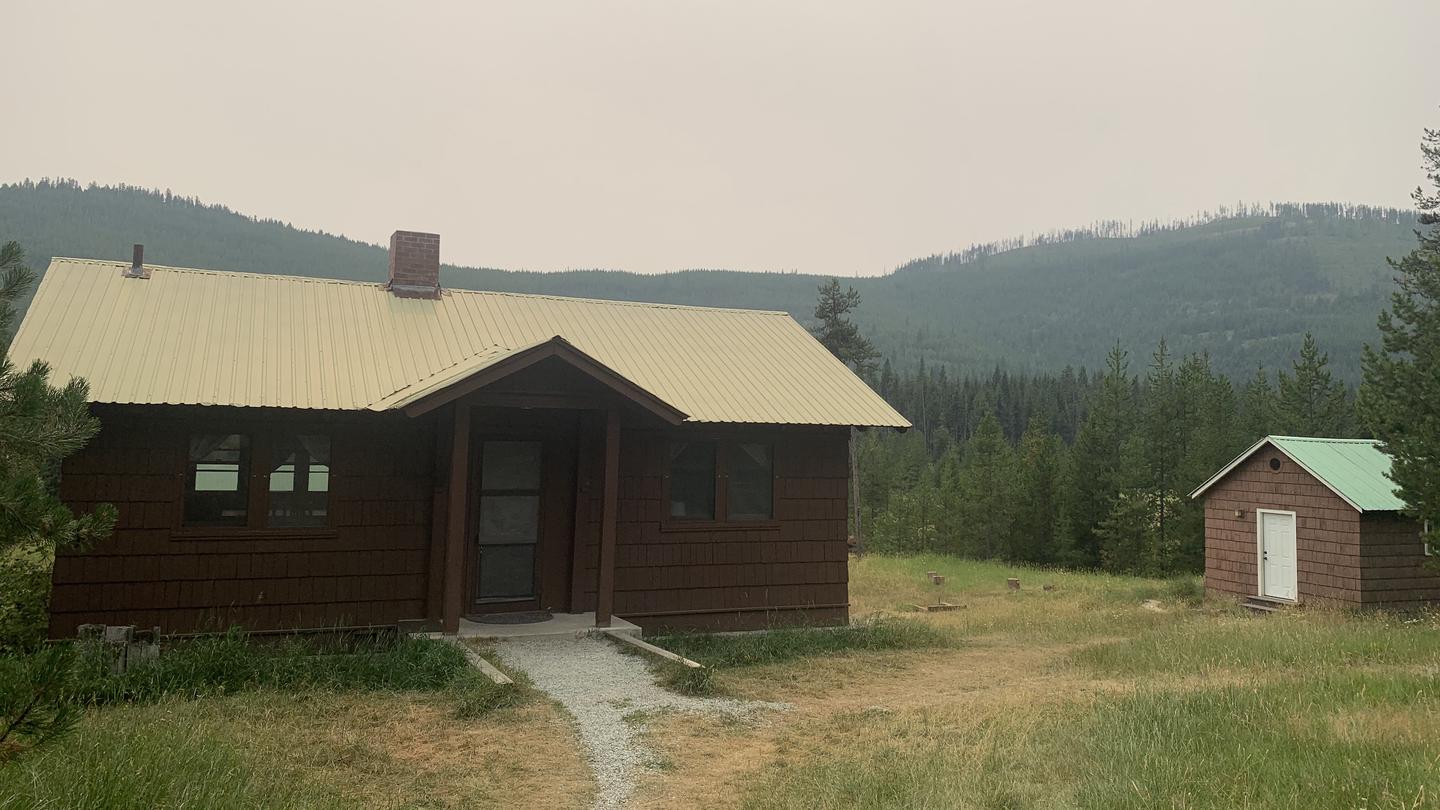 Historic forest service cabin with treed mountain behind.Star Meadow Guard Station and bunk house.