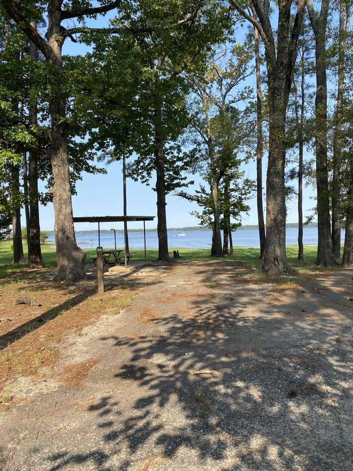 A photo of Site 063 of Loop B at MILL CREEK (TEXAS) with Picnic Table, Electricity Hookup, Fire Pit, Shade, Waterfront, Lantern Pole, Water Hookup, Lean To / Shelter