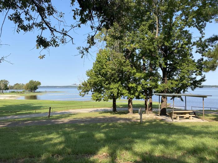 A photo of Site 075 of Loop C at MILL CREEK (TEXAS) with Picnic Table, Electricity Hookup, Fire Pit, Shade, Food Storage, Waterfront, Lantern Pole, Water Hookup, Lean To / Shelter