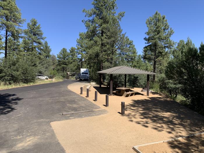 A photo of Site 05 of Loop B at LYNX CAMPGROUND with Picnic Table, Fire Pit, Shade. Two RV parking spots. Vault latrine in deep background. 