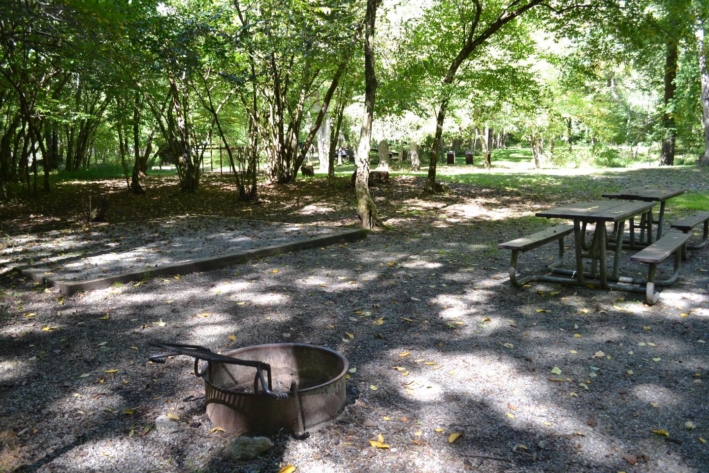 Site 2Tent pad, fire ring and picnic tables with horse stalls shown in background