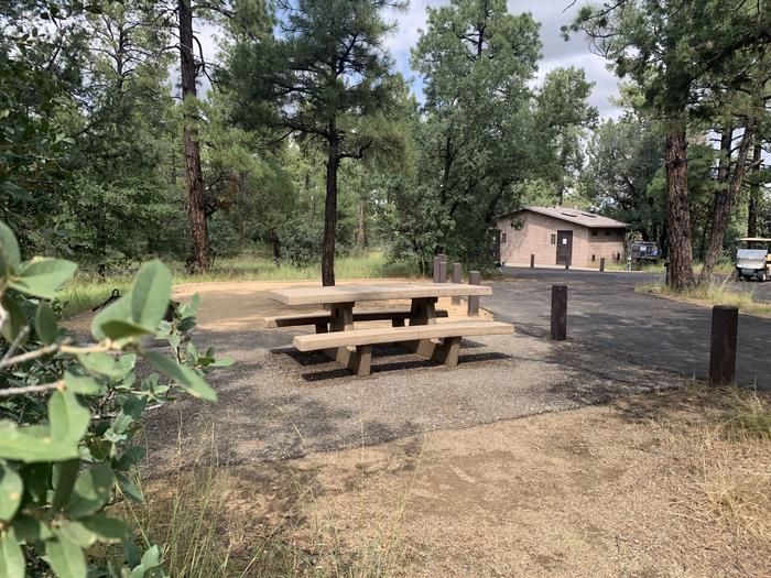 A photo of Site 21 of Loop E at LYNX CAMPGROUND with Picnic Table, Fire Pit with drive-they parking and flush toilets in the background. 