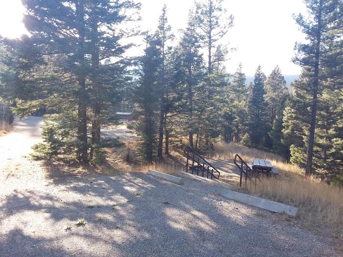 Lower Loop Site 7 with picnic table, steps and fire pit shaded by surrounding forest
