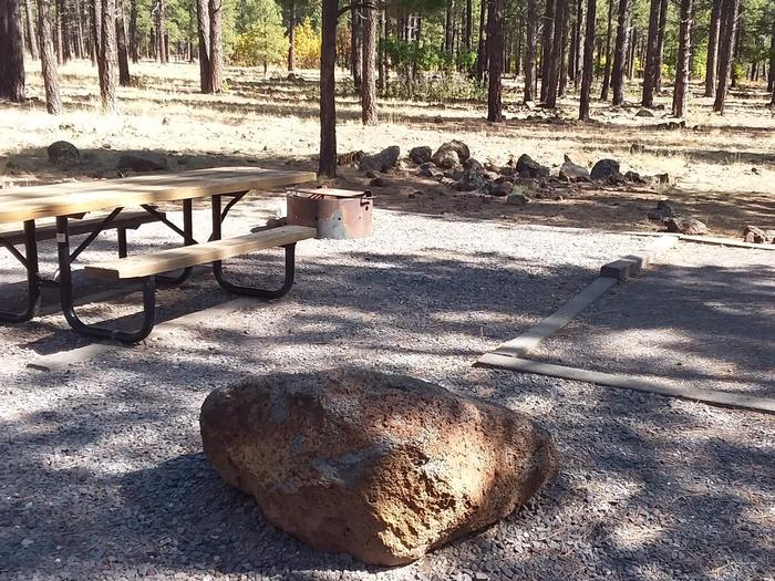 Site 8 table and grill, with large stone, and rocky area behind it.Campsite 8