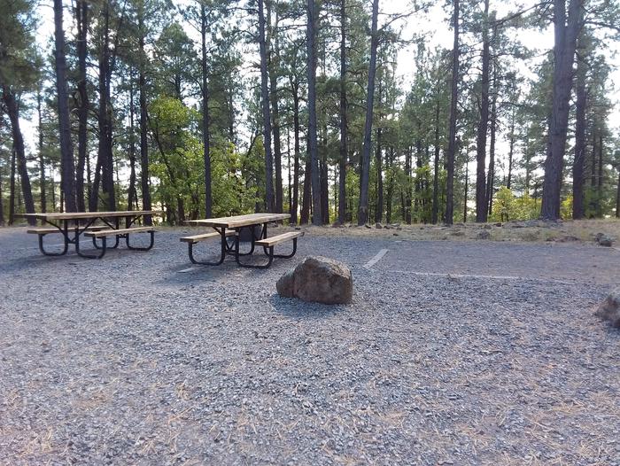 Site 30 with two tables in a gravel area next to a rock.Campsite 30 