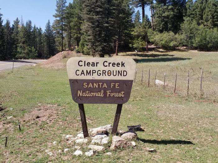 A campground sign with spruce trees and clear blue skies in the background.Clear Creek Campground Sign