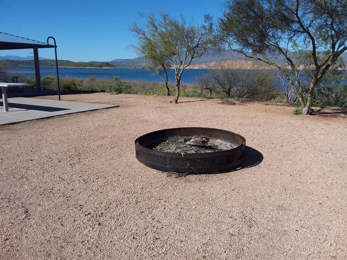 Campfire ring in front of a lake view with trees and mountains on the horizonFrazier Campground Campfire ring