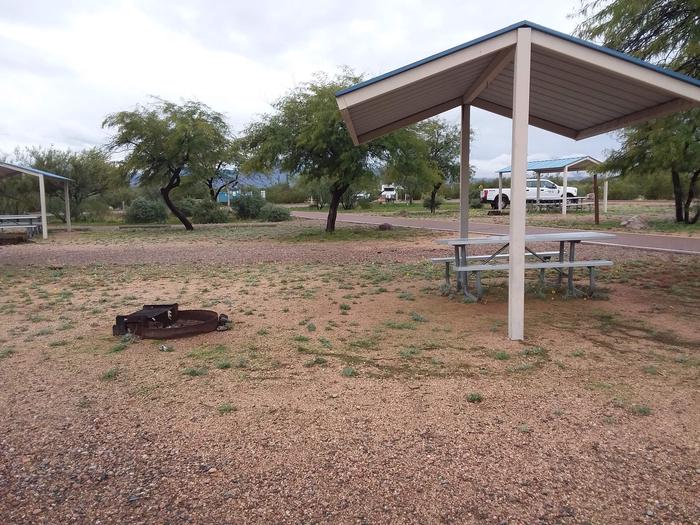Campsite 175 sideview with a firepit and a picnic table under the metal ramada