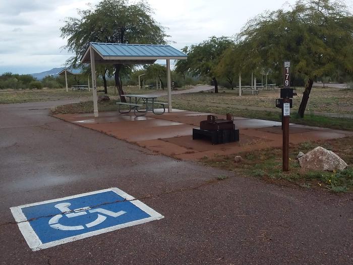 Handicap accommodating Campsite 179 with a firepit and covered picnic table on a paved patio