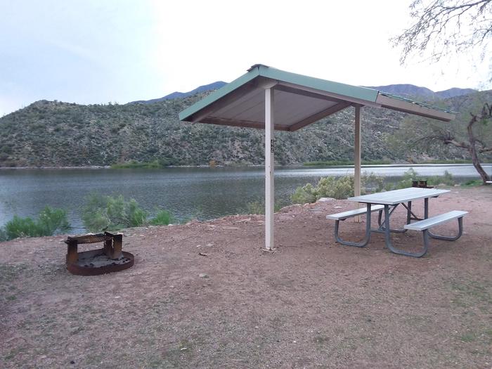 Site 42 with a picnic table fire ring, camp grill, shade structure, and parking.