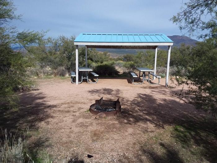 Site 16 with picnic tables, a fire ring, shade structure, and parking.