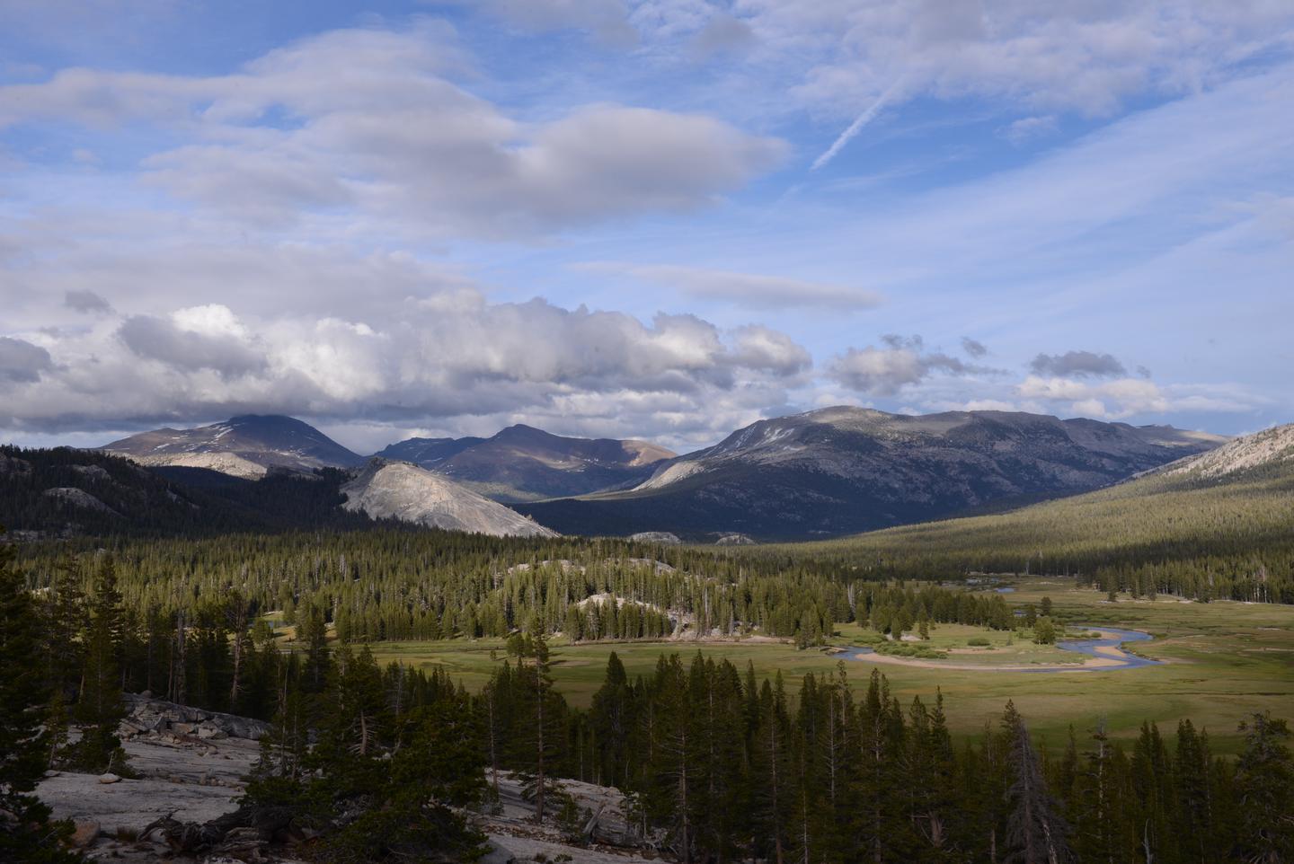 View of a large meadow, a river and distant peaks.Tuolumne Meadows in the spring. 